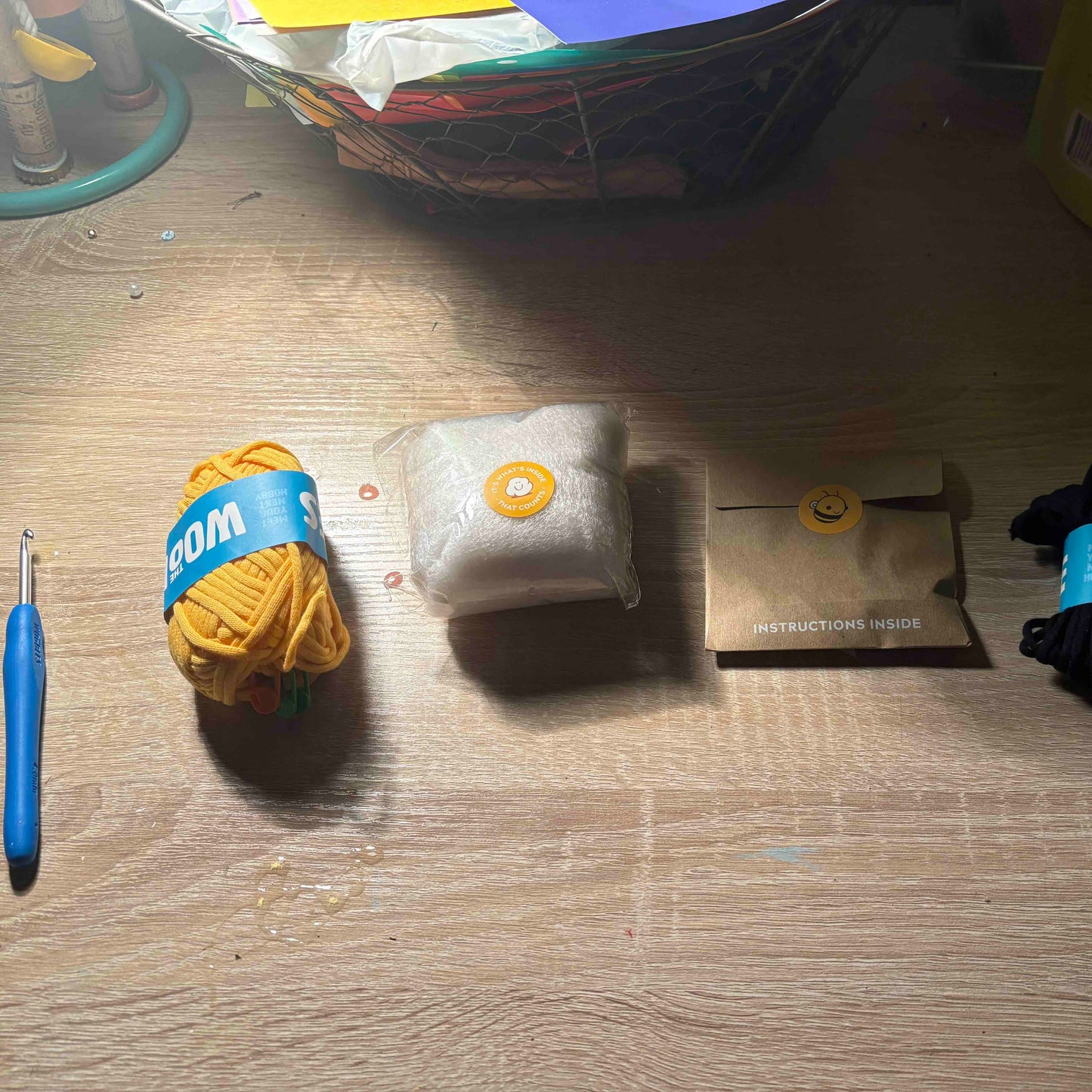 Yarn ball, crochet hook, and other crafting items on a wooden surface