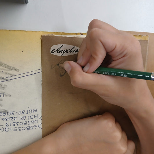 Person writing on a cardboard box with a green pen